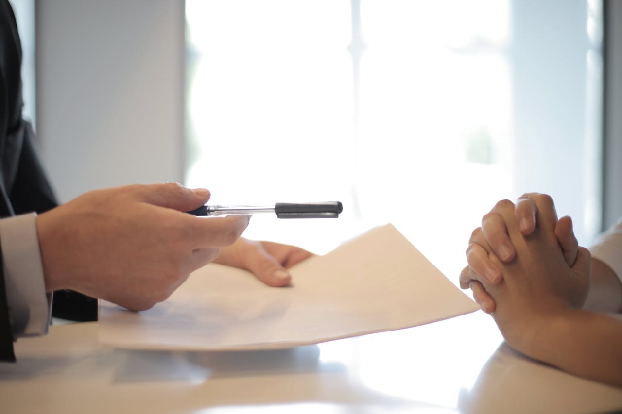 about-01 Close-up of a contract signing with hands over documents. Professional business interaction.